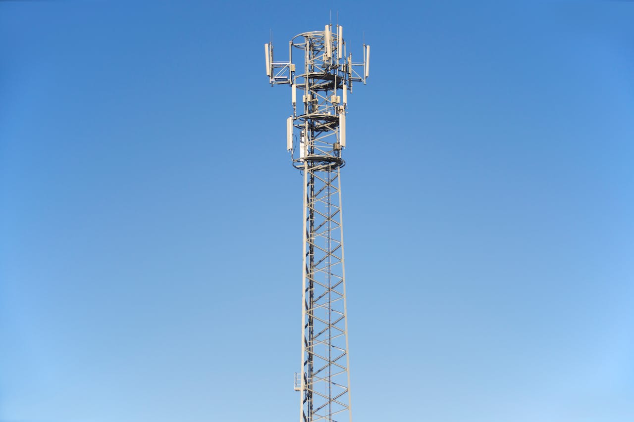 A tall cell tower set against a clear blue sky, representing modern communication technology.