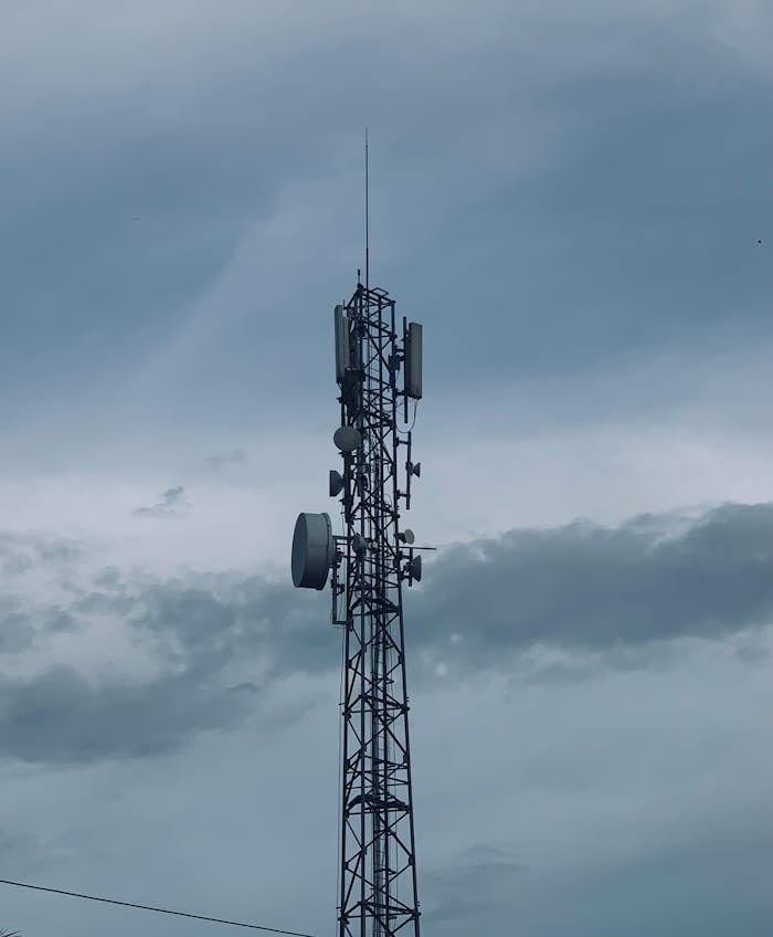 Telecommunications tower with antennas against a cloudy sky in Indonesia.