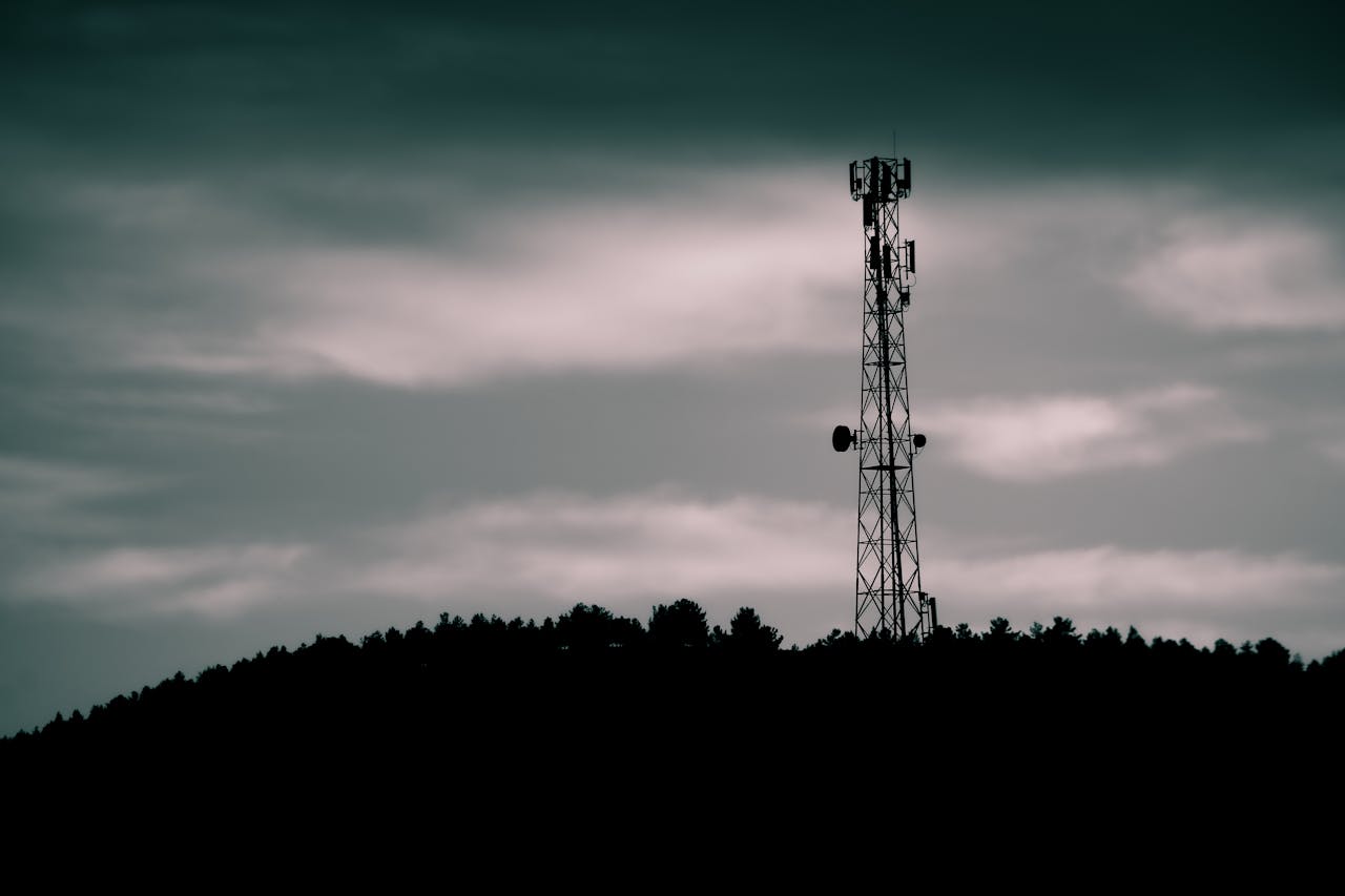 Dramatic silhouette of a telecommunication tower against a dusk sky, illustrating modern technology.